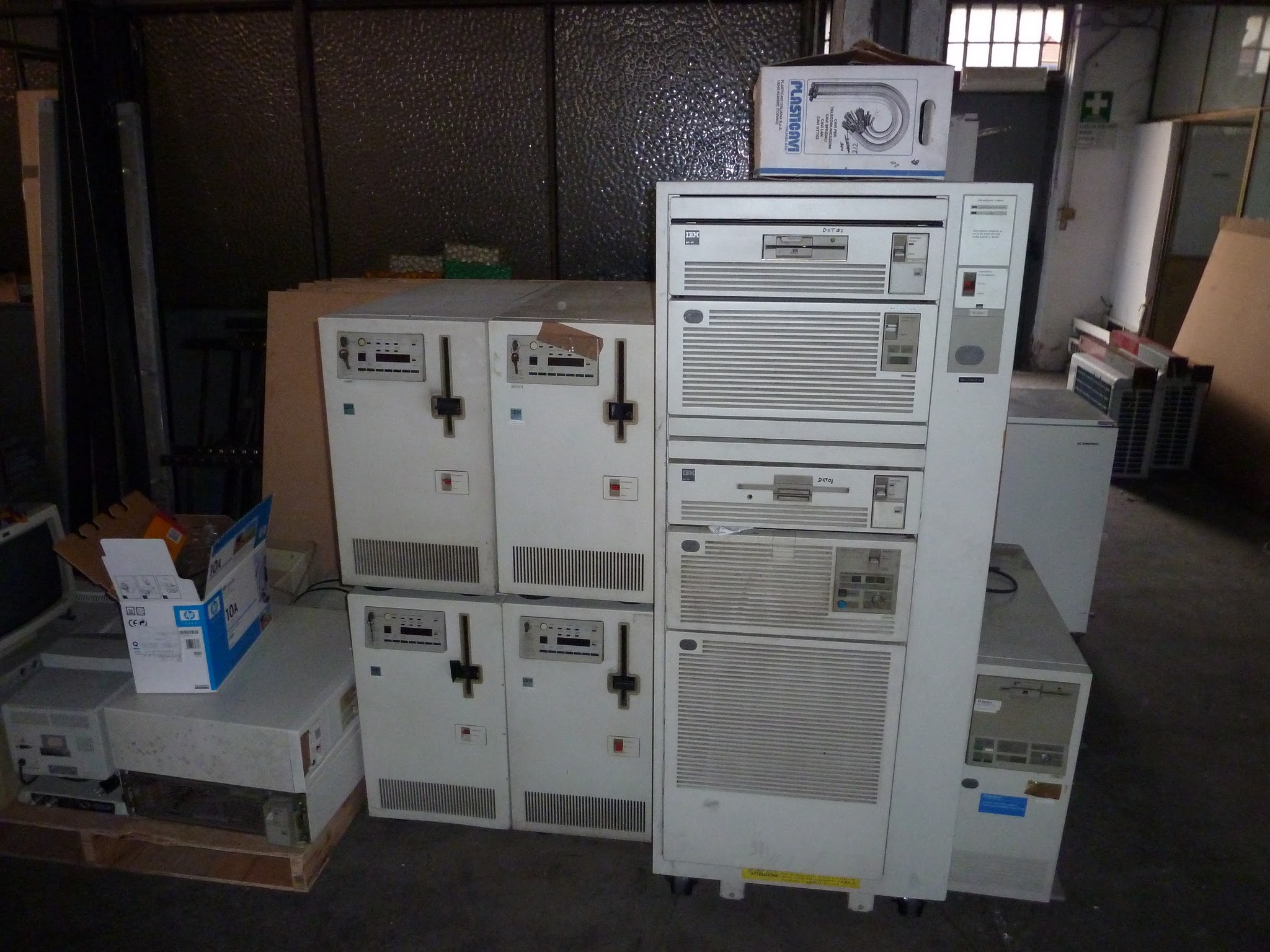 Tall vintage IBM rack and stacked beige computer cabinets in a dim warehouse