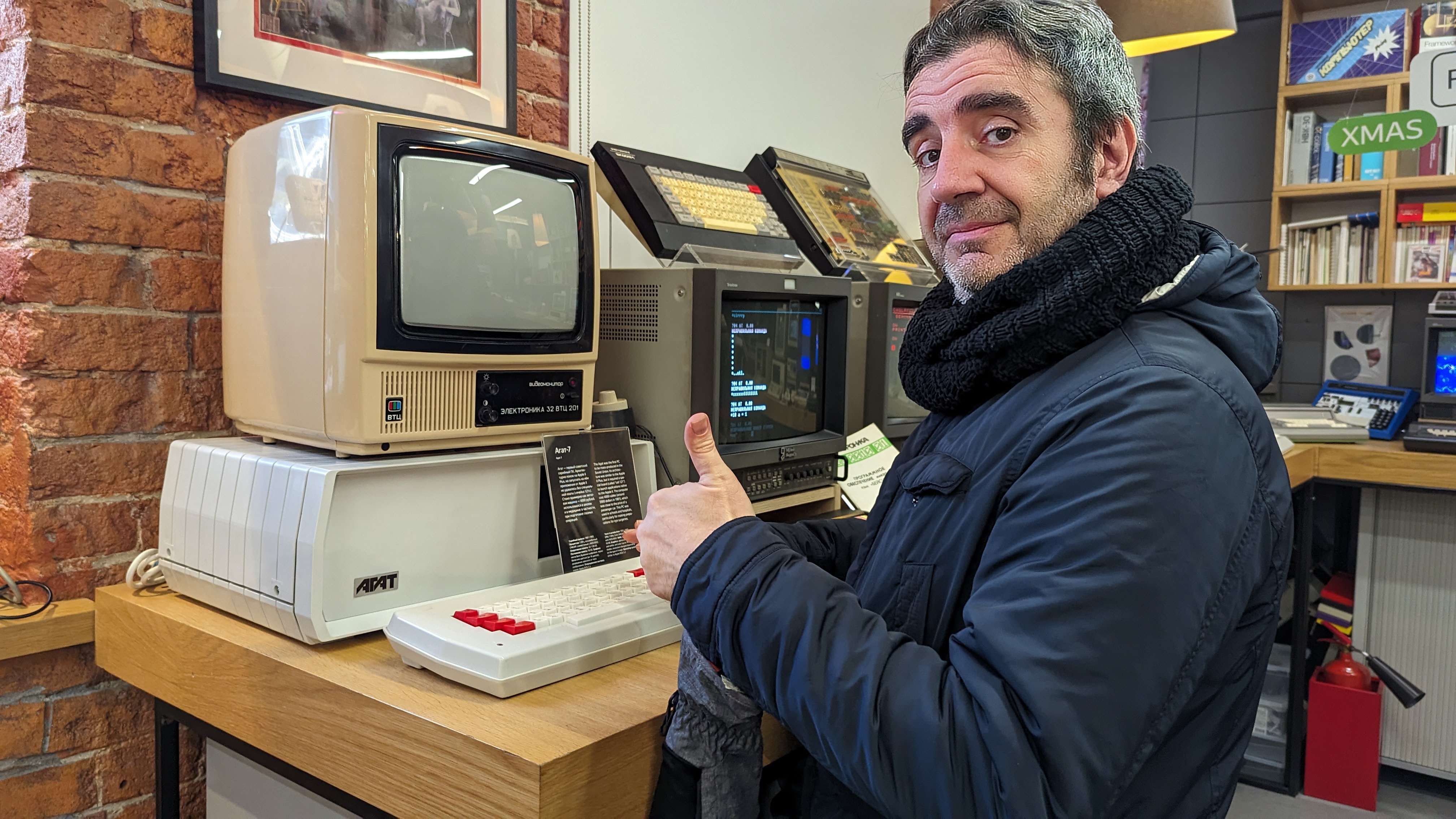 Andrea giving a thumbs-up beside an AGAT computer and a Cyrillic-labelled CRT monitor in a museum room